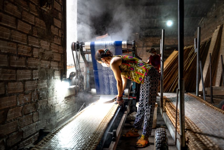 A woman working in an industrial carpet workshop, operating machinery with focus.