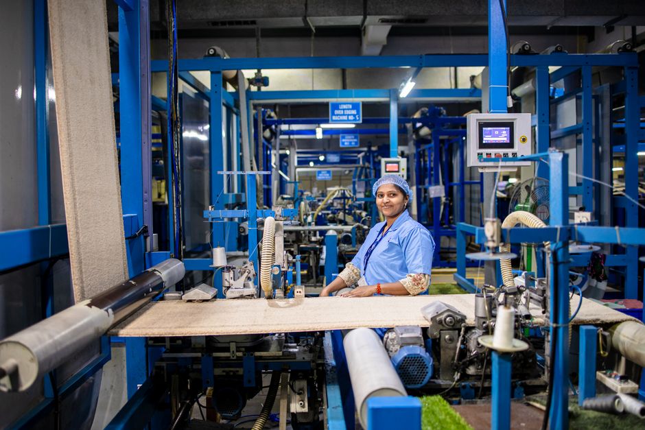 Smiling female textile worker operating machinery in a modern factory environment.